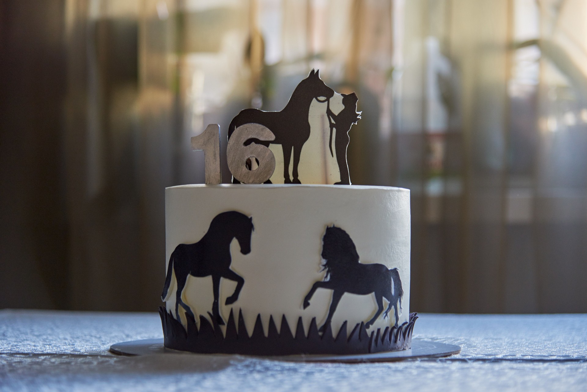 A birthday cake decorated with figures of horses and candles on the table .