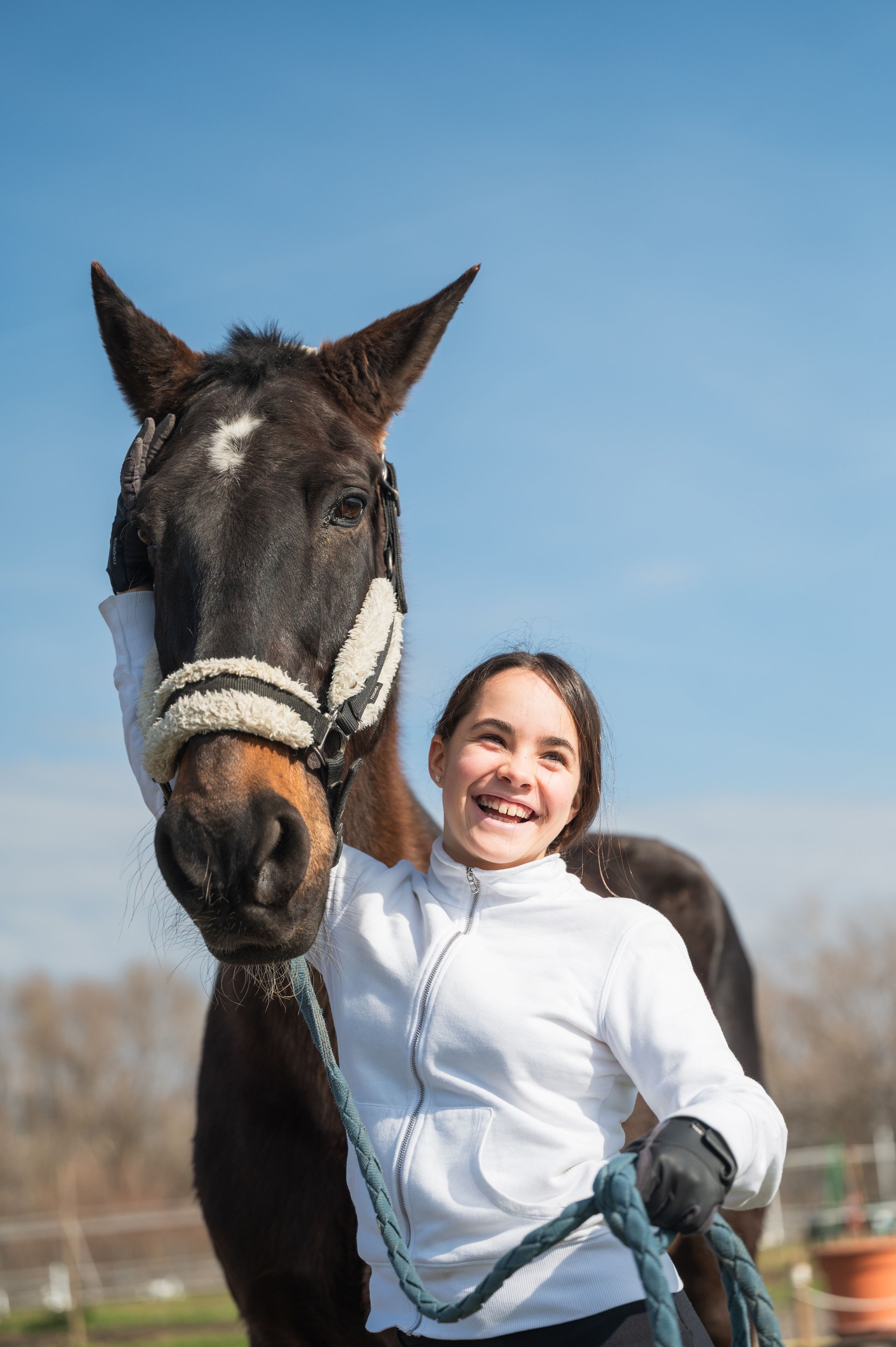 Young horse rider smiling and holding the reins of her horse